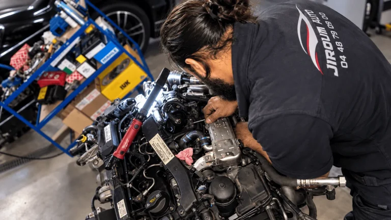 Mécanicien Jiroum Auto intervenant sur un moteur déposé dans l’atelier